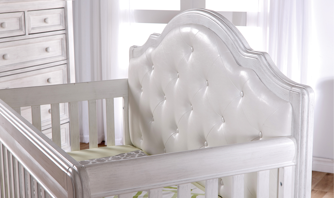 The <b>2202 Cristallo Forever Crib</b> in Vintage White and with a <b>white vinyl upholstered panel</b> headboard. 